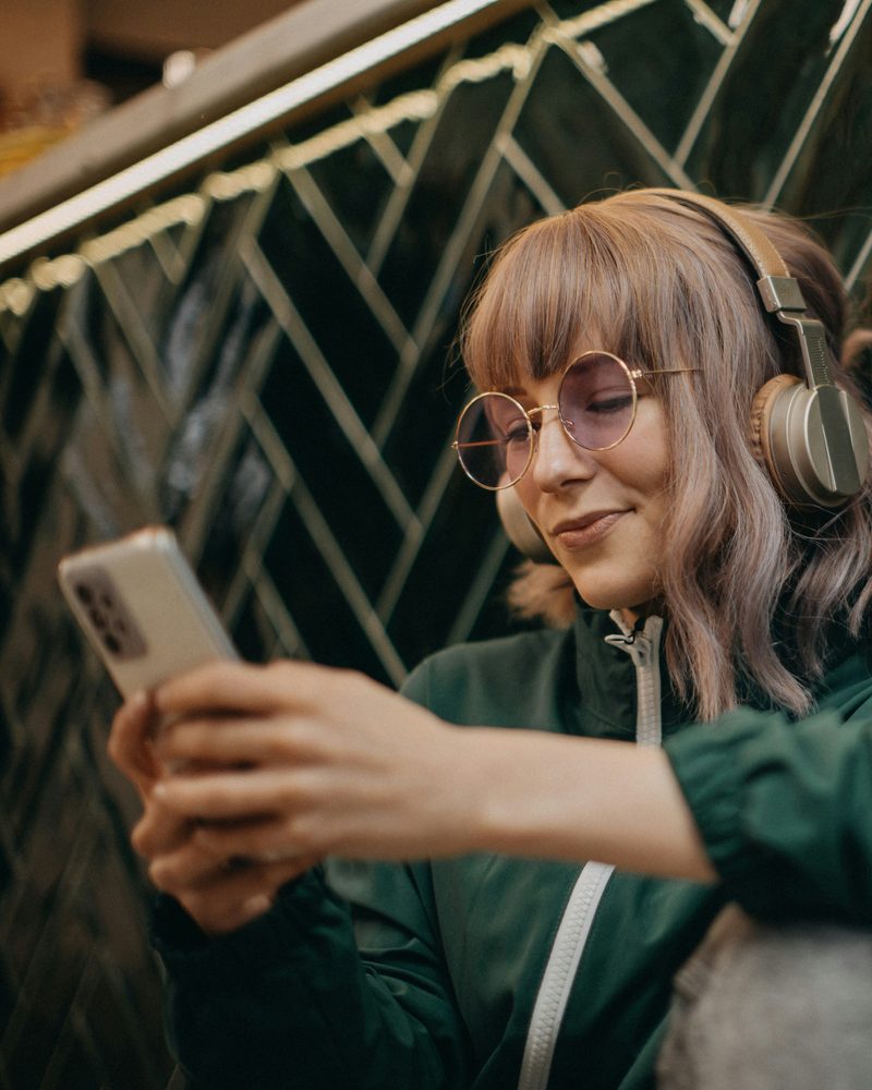A fan in headphones smiling at her phone